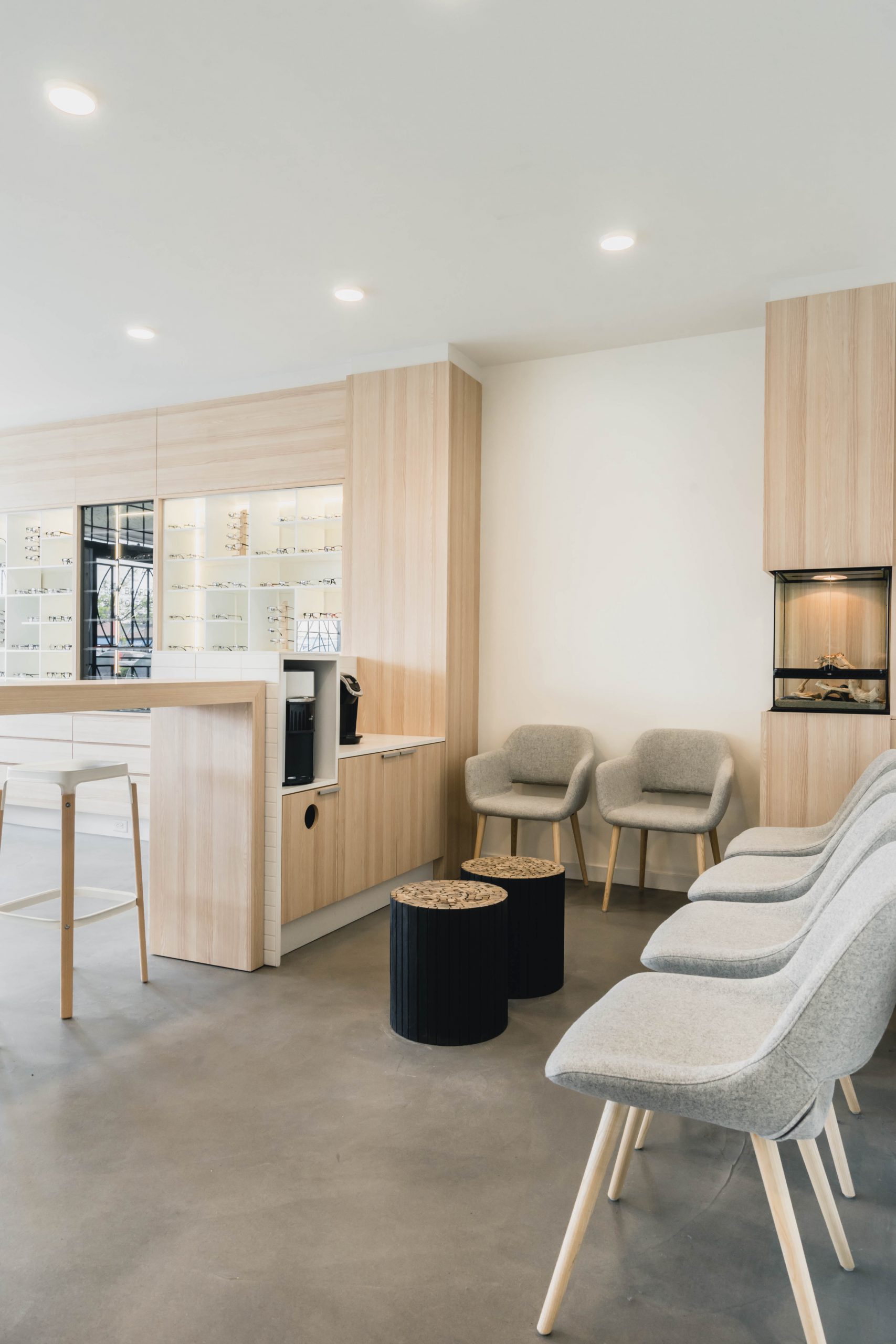 Optometrist clinic interior showing customer waiting area, chairs, and cabinetry