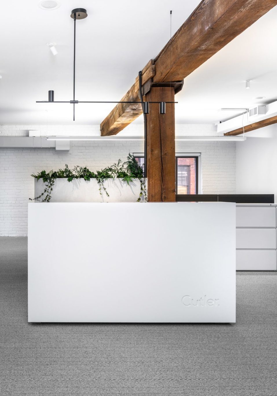 Cutler Architecture & Interior Design office reception desk client waiting area with light fixture over hanging and white desks and walls