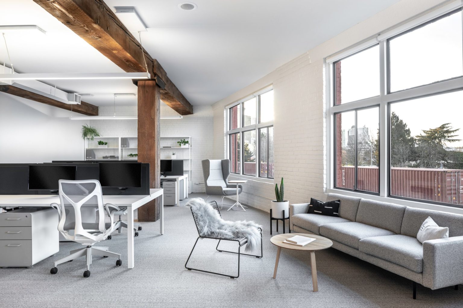 Workstation with a fully adjustable mesh task chair and a lounge setting nearby at Cutler's Vancouver studio