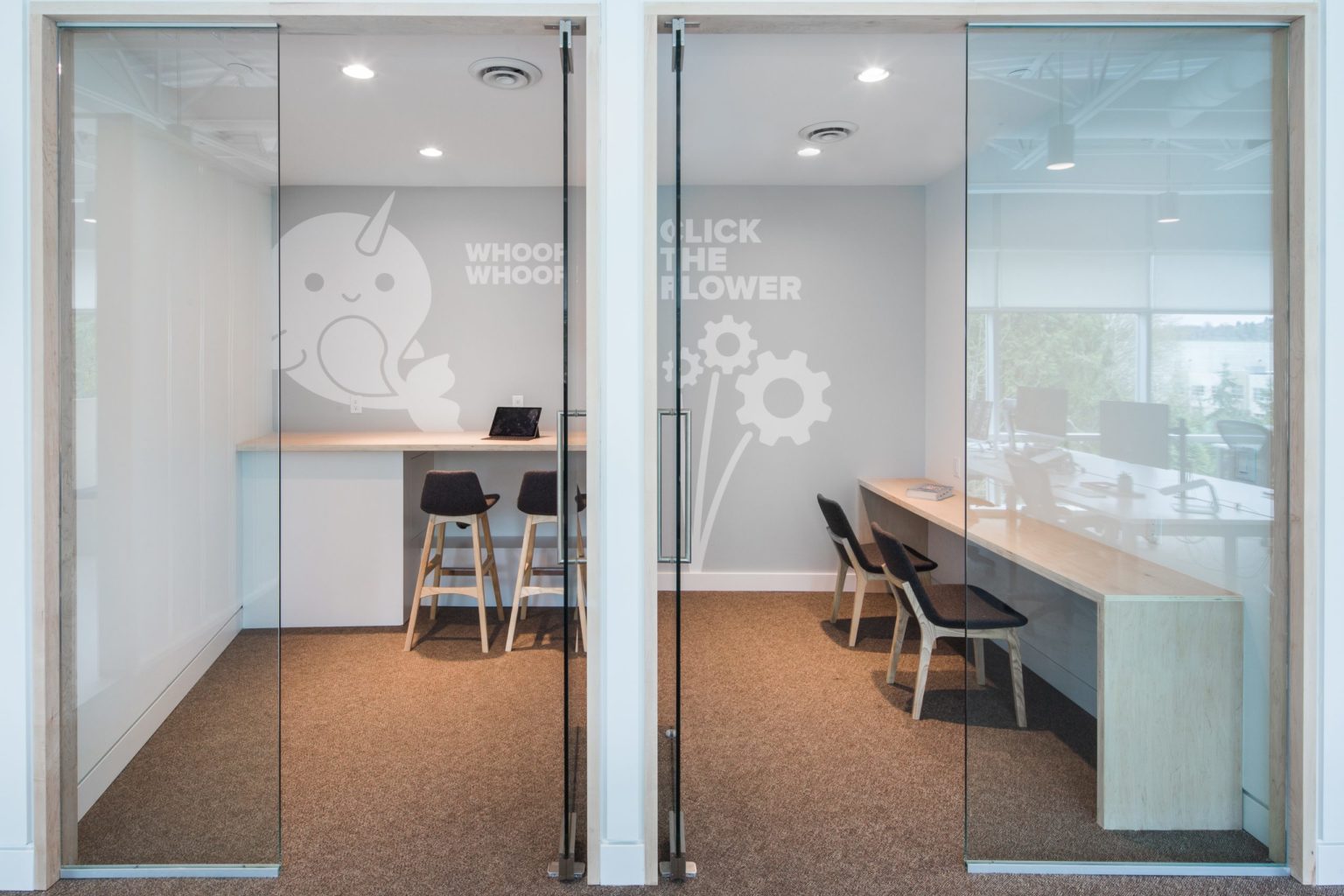 Pair of small glass-fronted focus rooms sized for one to two people in a hybrid office design