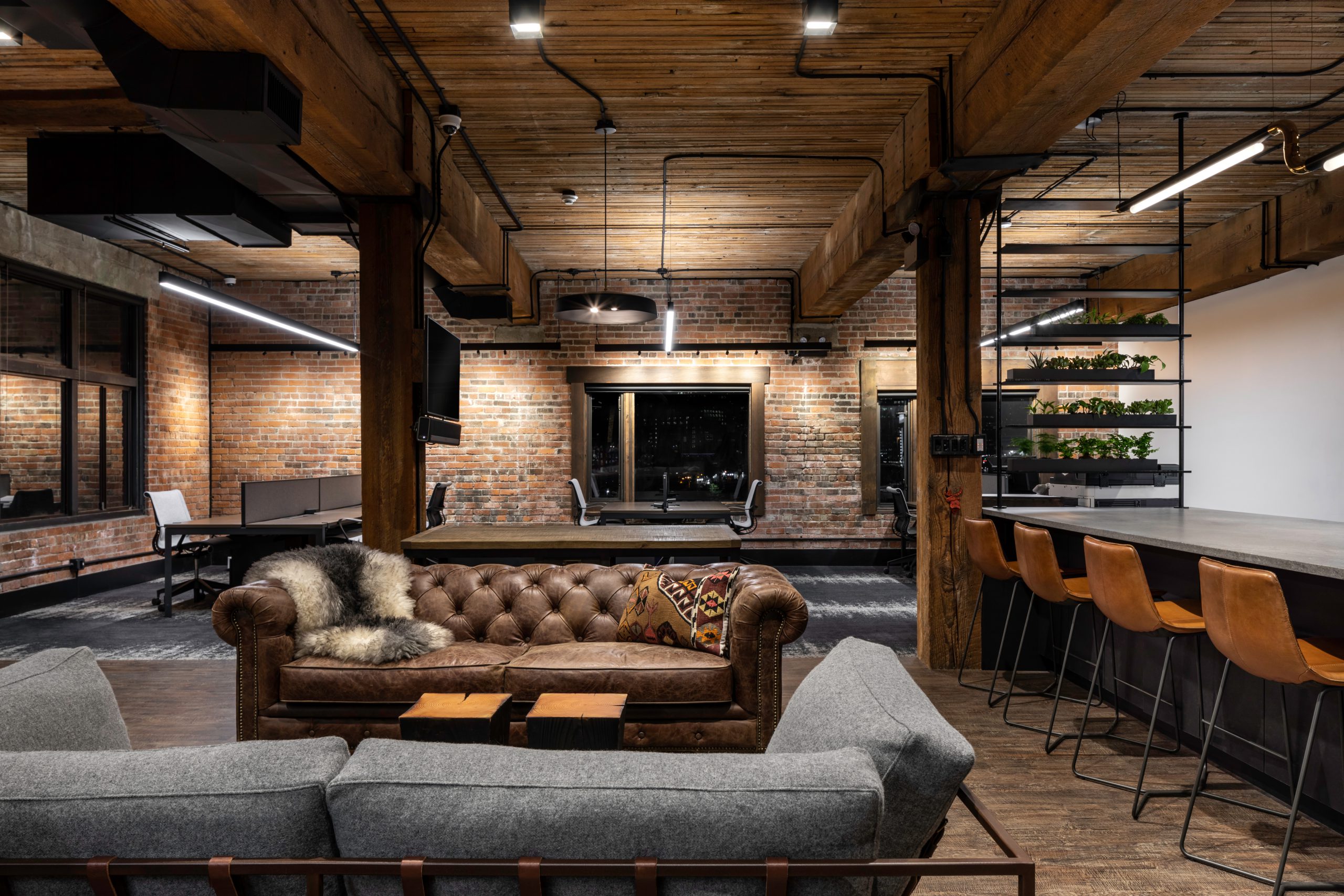 Corporate lounge and workstations at Key Marketing in Vancouver BC, showing bricks walls, wooden pillars, bar, couches, and lighting fixtures