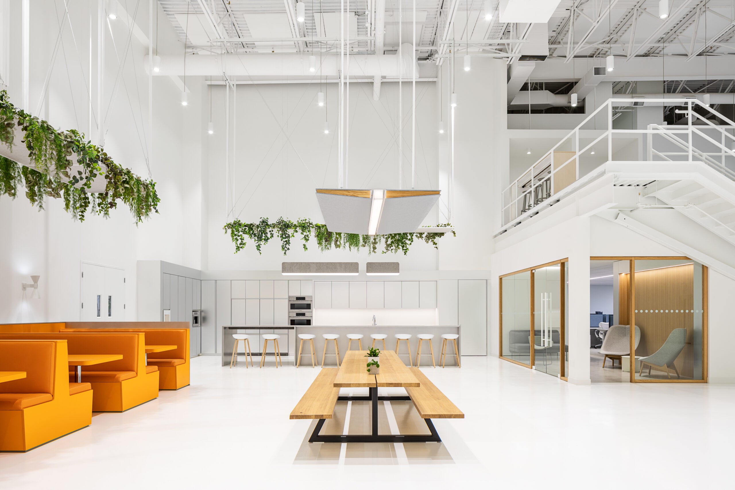 Corporate cafeteria design at Keirton headquarters in Surrey BC, with bright orange seating, white walls, and overhanging plants