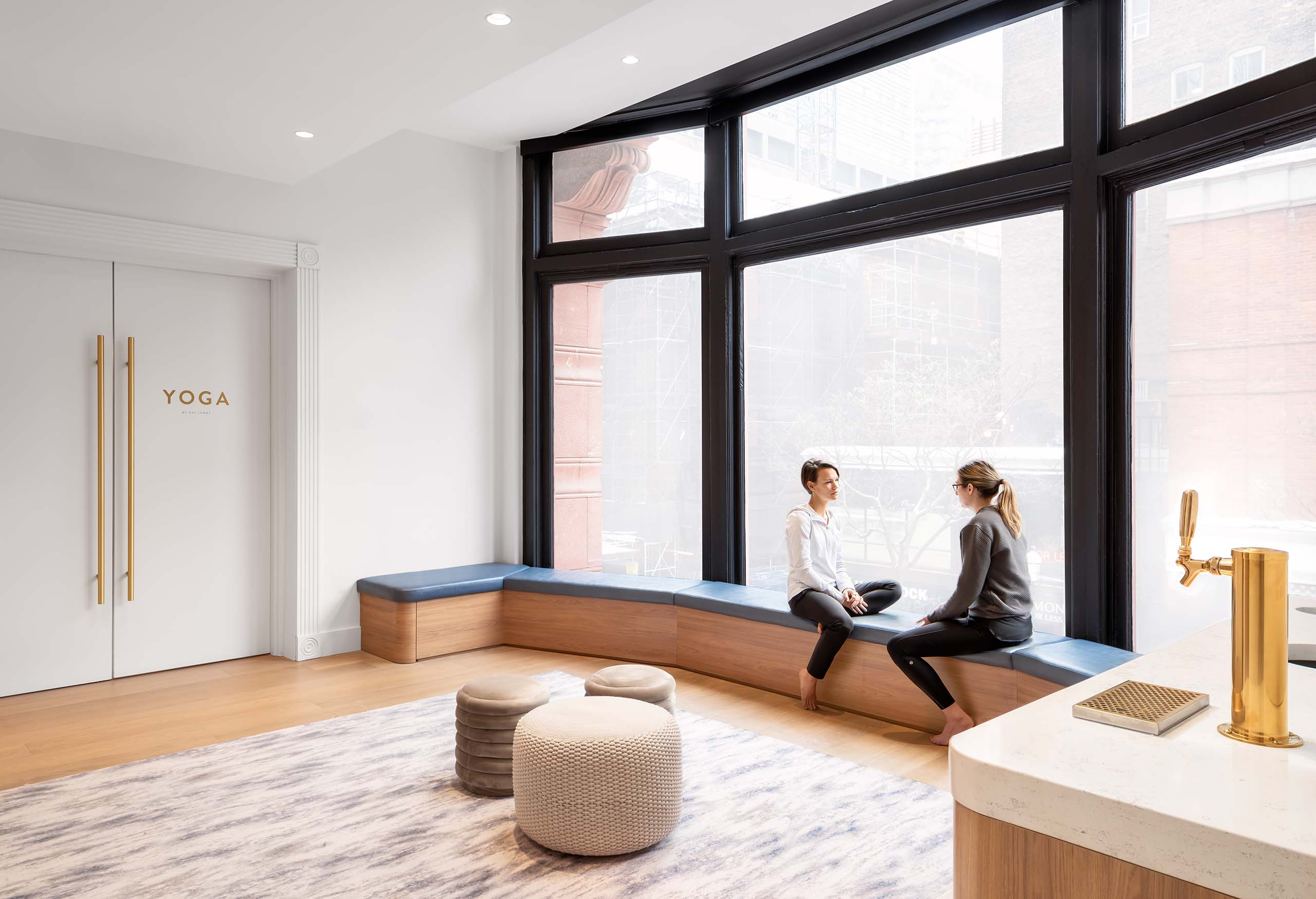 Sweat and Tonic yoga studio interior with 2 people talking by the window, located in Toronto ON, fitness architecture and design by Cutler