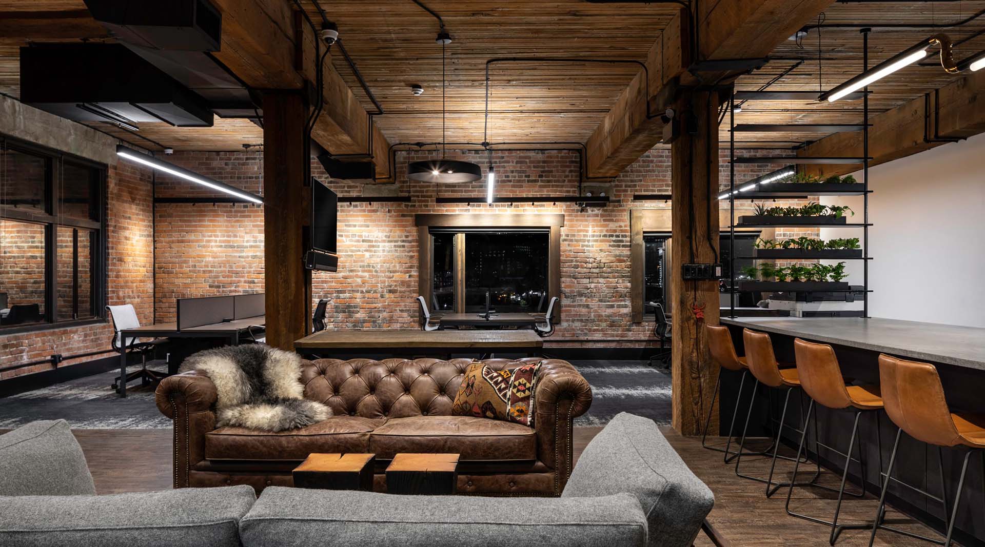 Corporate lounge and workstations at Key Marketing in Vancouver BC, showing bricks walls, wooden pillars, bar, couches, and lighting fixtures