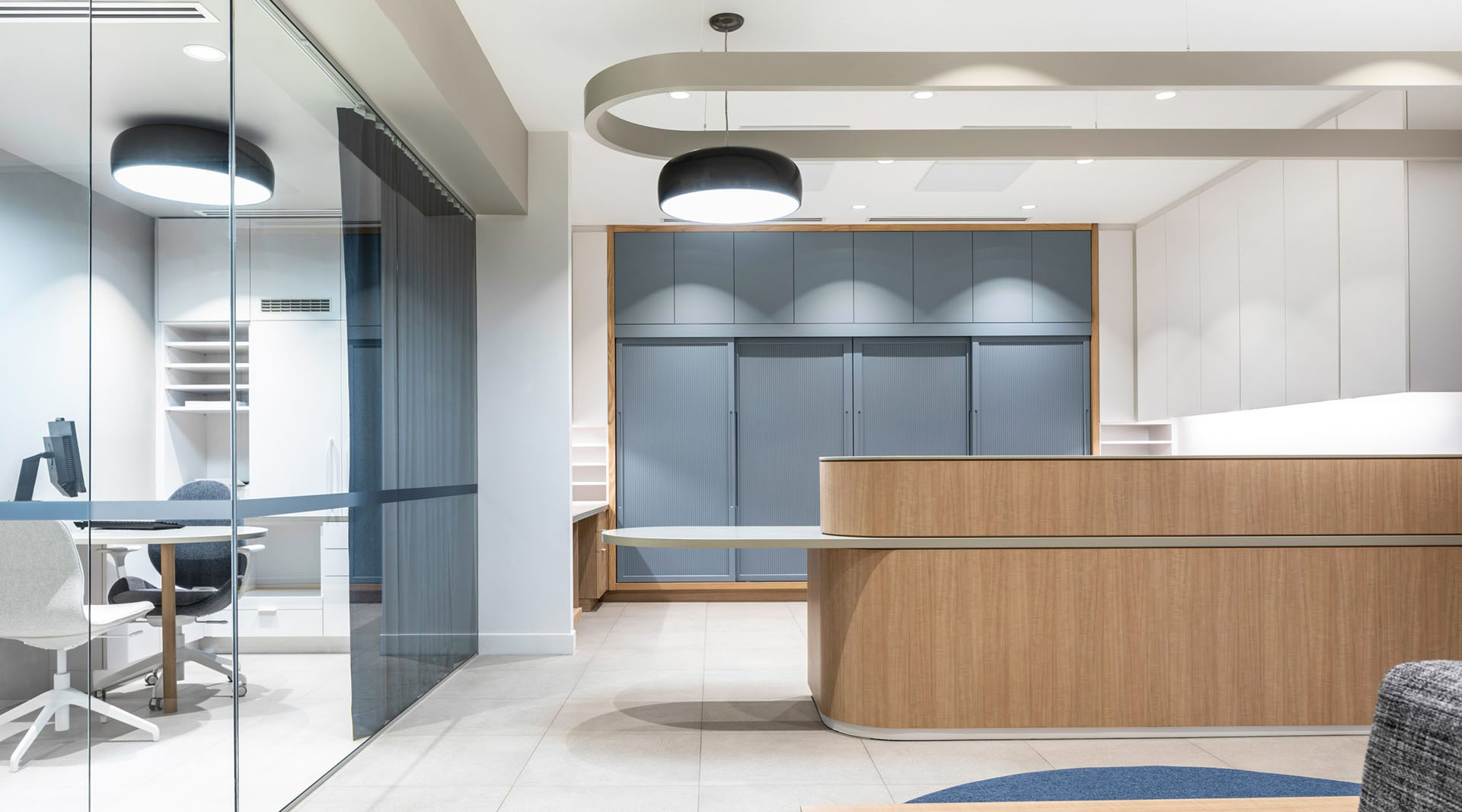 Dental office interior showing reception desk, lighting fixtures, glass walls for the consultation room, and patient waiting area