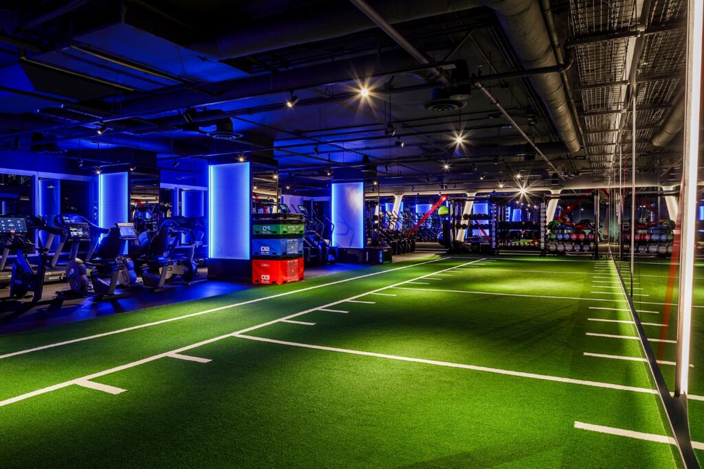Gym interior design ideas in practice: a turf training zone beside a cardio bank in a Cutler-designed fitness facility