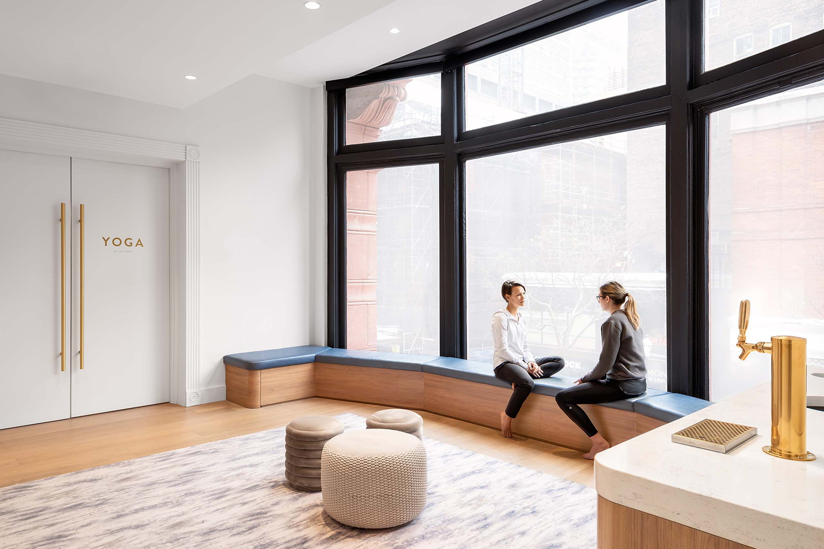 Sweat and Tonic yoga studio interior with 2 people talking by the window, located in Toronto ON, fitness architecture and design by Cutler