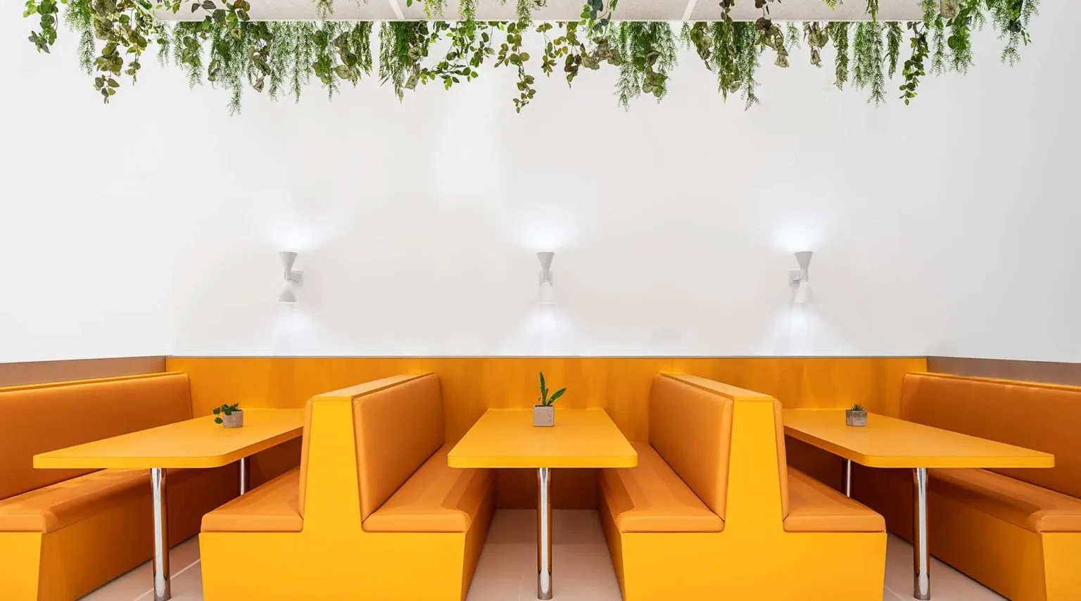 Biophilic restaurant design with greenery, warm banquette seating and natural materials